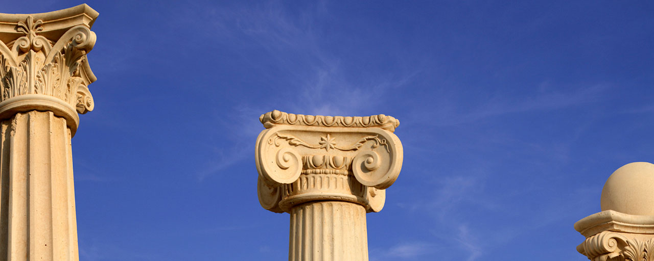 Three ancient greek columns against a blue sky